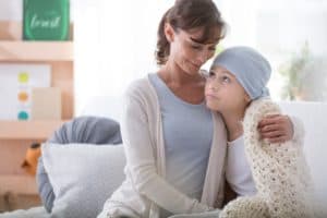 A young cancer patient is comforted by her mother