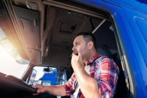Drowsy truck driver yawning while driving.