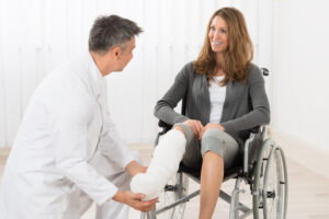 Doctor checking up woman on wheelchair with bandage.