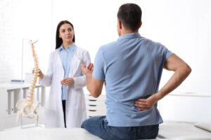 Man suffering from back & spine pain due to injury consulting doctor.