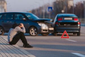 Driver sitting on the gutter frustrated on left turn accident.