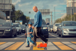 Father and son walking in the pedestrian lane while cars are stopping.