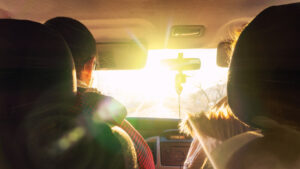 The man and the woman in the car rush towards to the dazzling sun.
