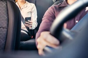 Lady passenger of uber car using her phone.