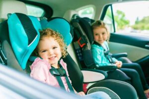 Toddlers seating in car seats for safety.