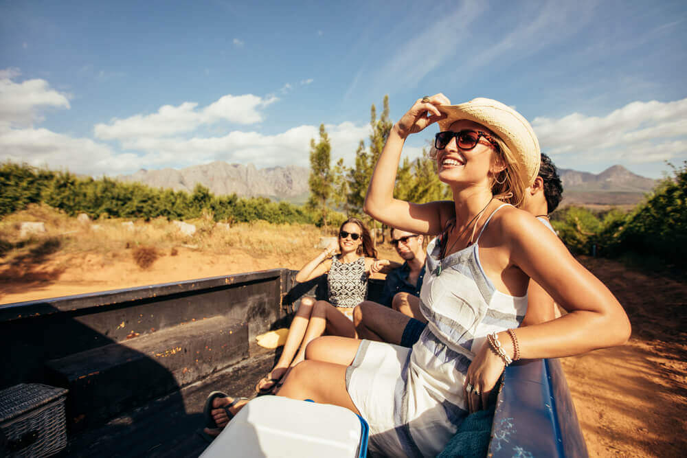 Happy lady passengers sitting in the truck bed.