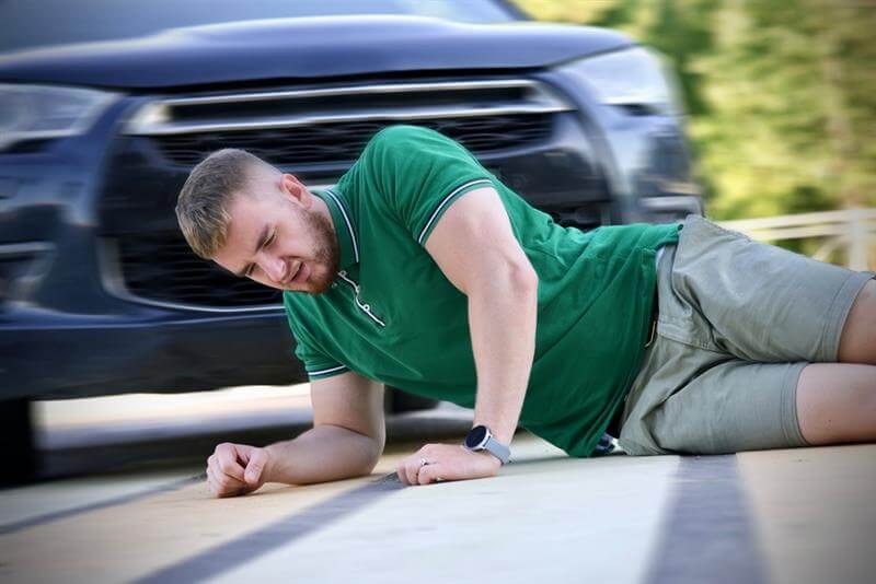 Pedestrian guy hit by careless driver in a car on the road while crossing highway.