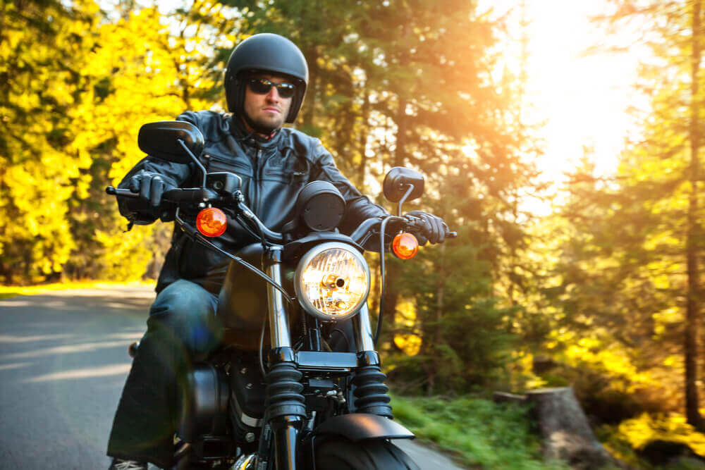 Motorcycle rider strolling in nature sunset background.