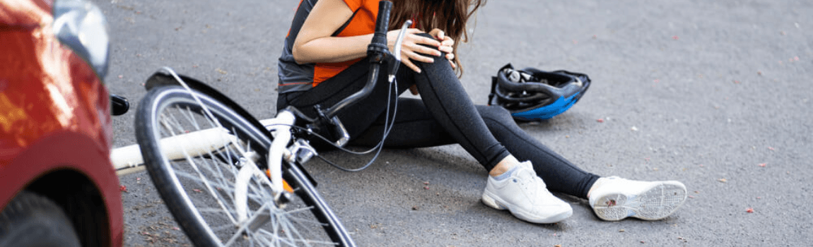 Lady cyclist in pain after accident in the road.