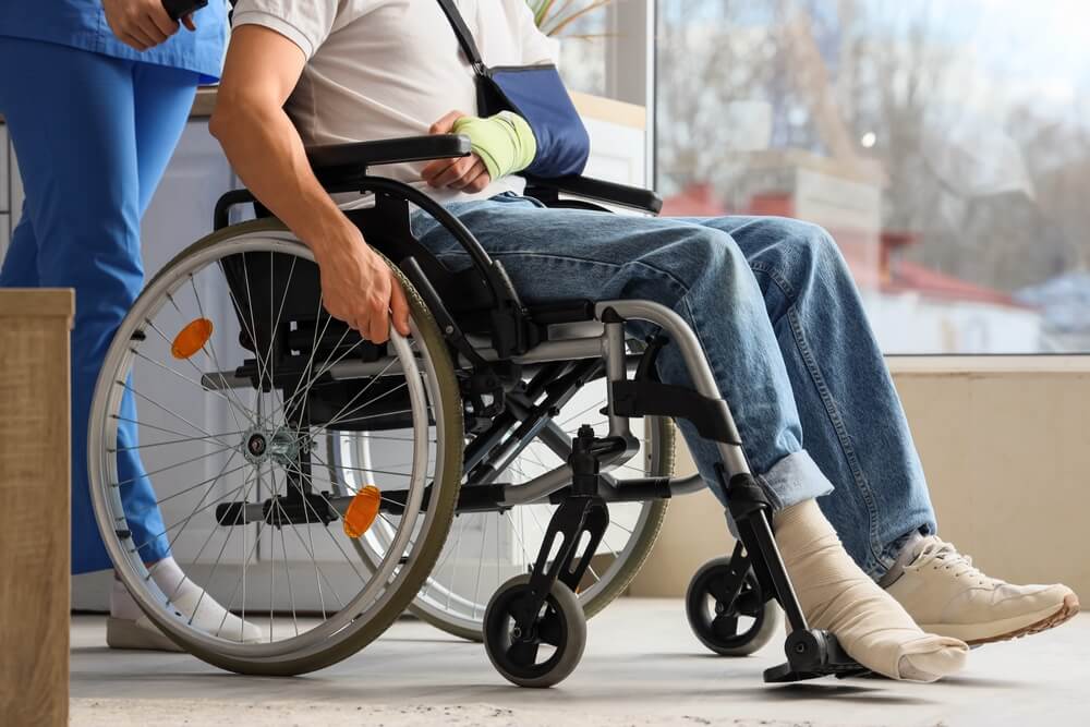 Injured young man in wheelchair after accident with doctor at home.